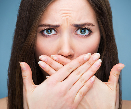 Worried woman with hands covering her mouth